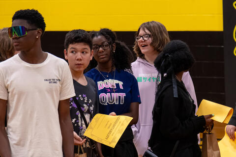 A group of eighth-grade students look off-camera while awards are being presented. 