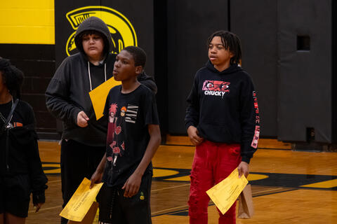 A few eighth-grade students hold awards in their hands while looking off-camera. 