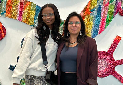 Student Londyn Carter poses with local artist Rebecca Nava Soto for a photo.