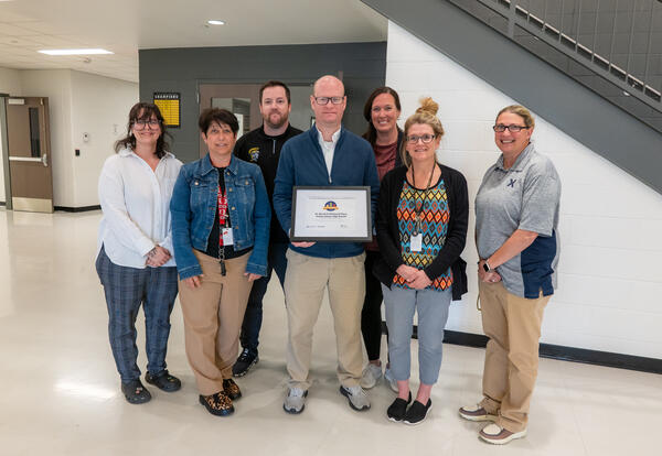 High school staff stand together for a picture while holding a 2025 Momentum Award.