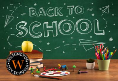 BAck to school on chalkboard with school supplies on desk