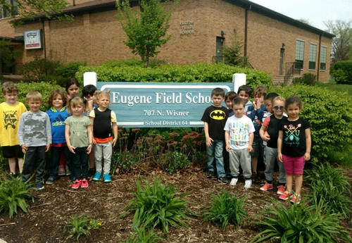 preschool students standing by Field school sign