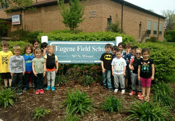 preschool students standing by Field school sign