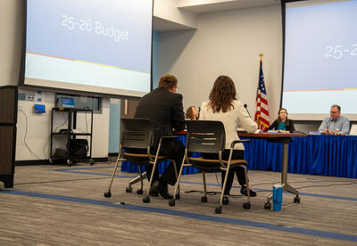 D64 admin sit down to give a presentation on the budget