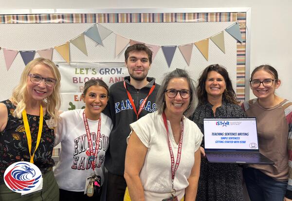 Group of Emerson Teachers and Kansas University Researchers together. One individual is holding up a laptop with a picture of the iSTAR logo on the screen.