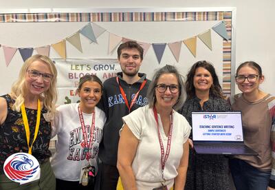 Group of Emerson Teachers and Kansas University Researchers together. One individual is holding up a laptop with a picture of the iSTAR logo on the screen.