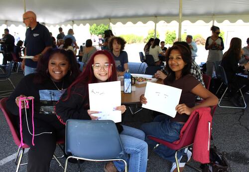students at a picnic holding up artwork