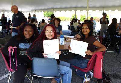 students at a picnic holding up artwork