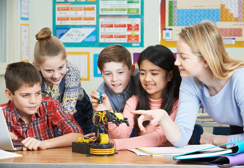 Picture of teacher working with students on a small robot