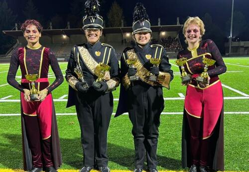 Band and color guard students pose with their trophies in Auburn