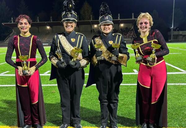 Band and color guard students pose with their trophies in Auburn