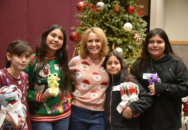 a woman and four girls stand in front of a Christmas tree.