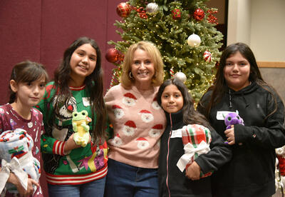 a woman and four girls stand in front of a Christmas tree.
