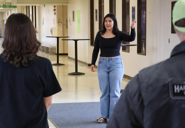 A girl faces the camera with her hand raised