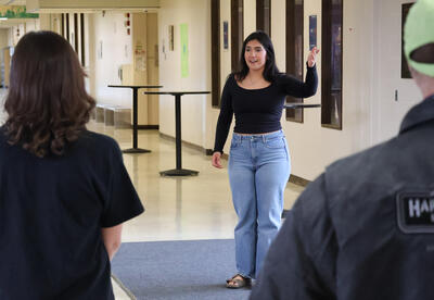 A girl faces the camera with her hand raised