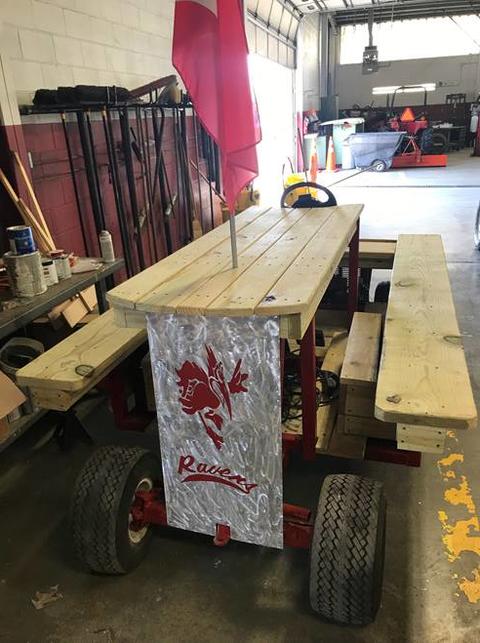 Wooden picnic table built on a lawnmower base.