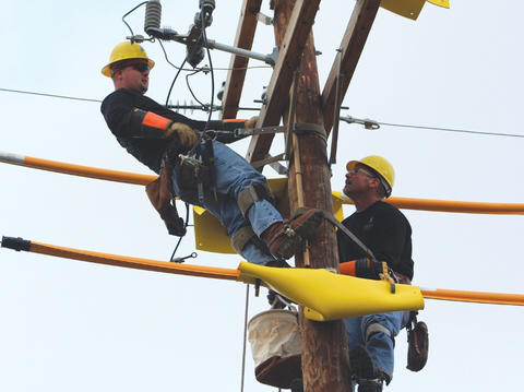 Two Linemen Working at Top of Utility Pole