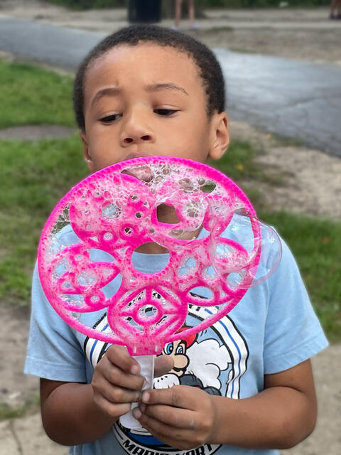 photo of young child blowing bubbles