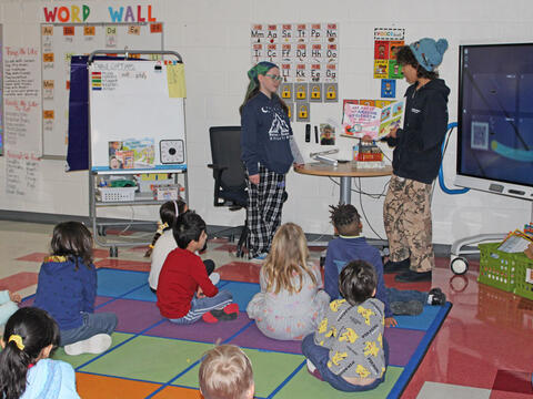 photo of big kid students reading to little kid students