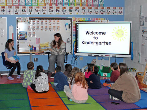 photo of big kid students reading to little kid students