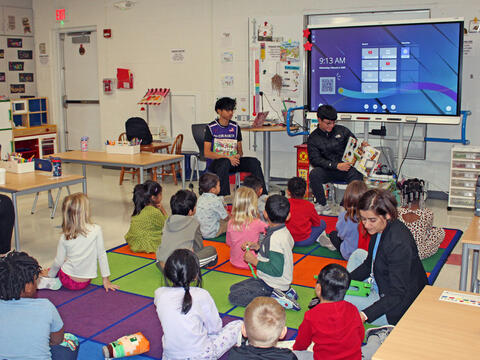 photo of big kid students reading to little kid students