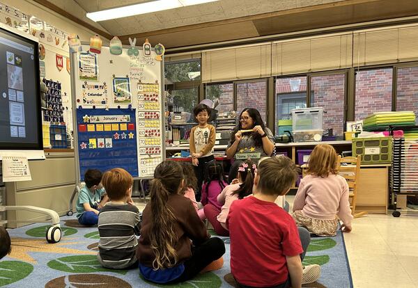 students sitting on rug with teacher