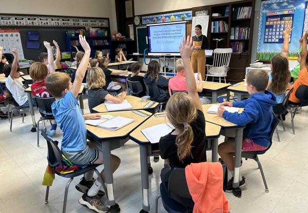 classroom with students raising hands